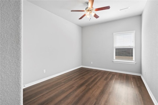 empty room featuring visible vents, baseboards, dark wood finished floors, and a ceiling fan