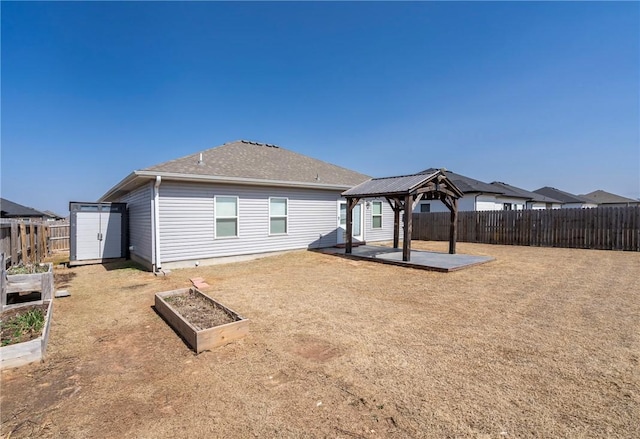 rear view of property featuring a gazebo, a patio, a vegetable garden, and a fenced backyard