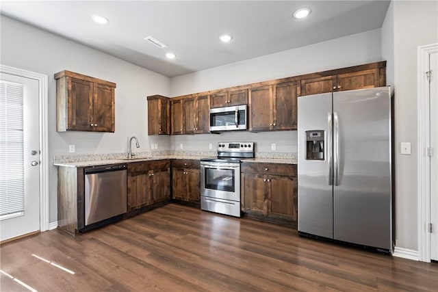 kitchen with a sink, stainless steel appliances, visible vents, and dark wood-style flooring