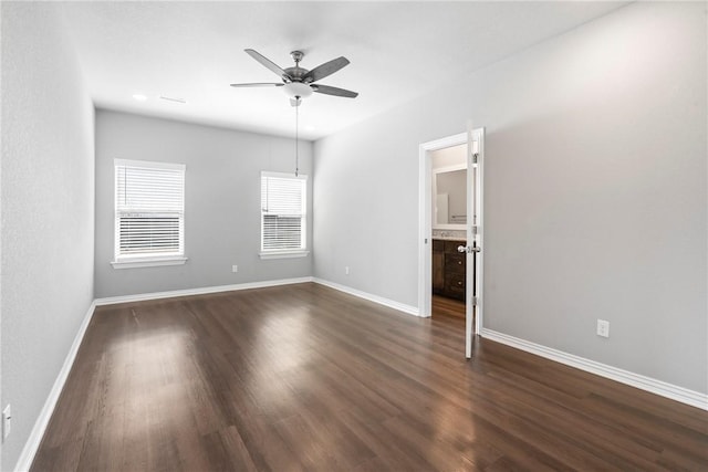 empty room featuring baseboards, a ceiling fan, and dark wood-style flooring