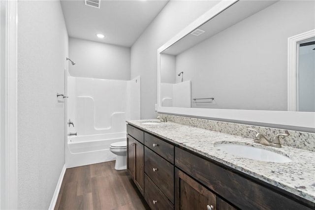 bathroom featuring a sink, toilet, wood finished floors, and double vanity