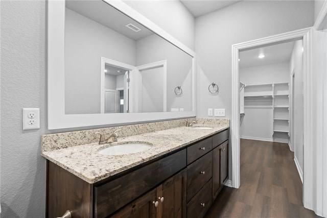 bathroom with a sink, visible vents, wood finished floors, and double vanity