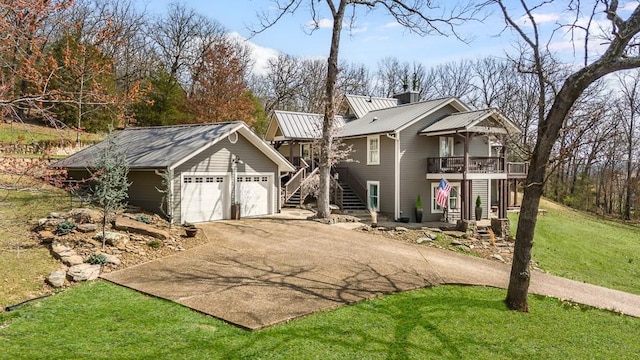 view of front facade featuring driveway, stairway, a front yard, a garage, and a chimney