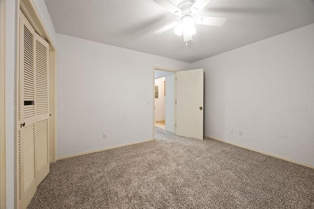 unfurnished bedroom with a closet, carpet flooring, a textured ceiling, and a textured wall