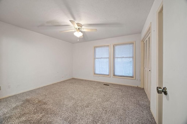 spare room featuring carpet flooring, visible vents, a textured ceiling, and ceiling fan