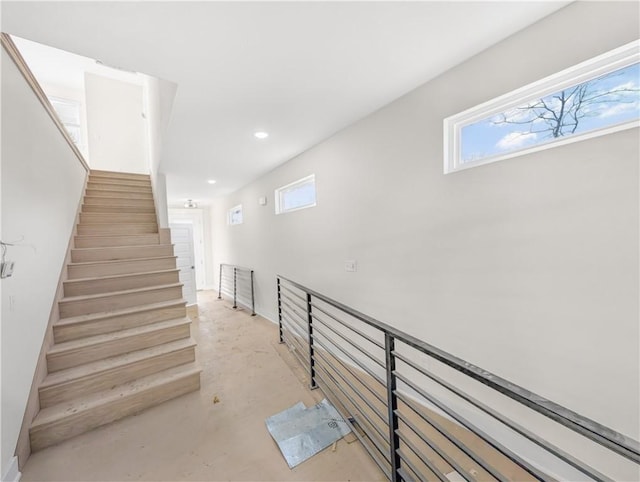 staircase with recessed lighting and concrete floors