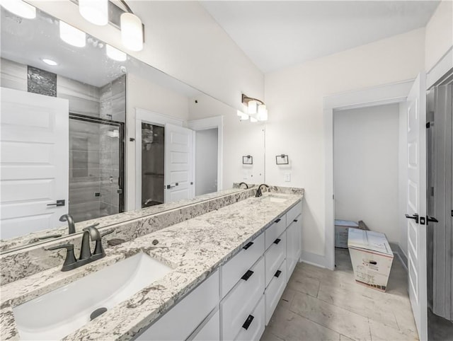 bathroom featuring a sink, baseboards, double vanity, and a shower stall