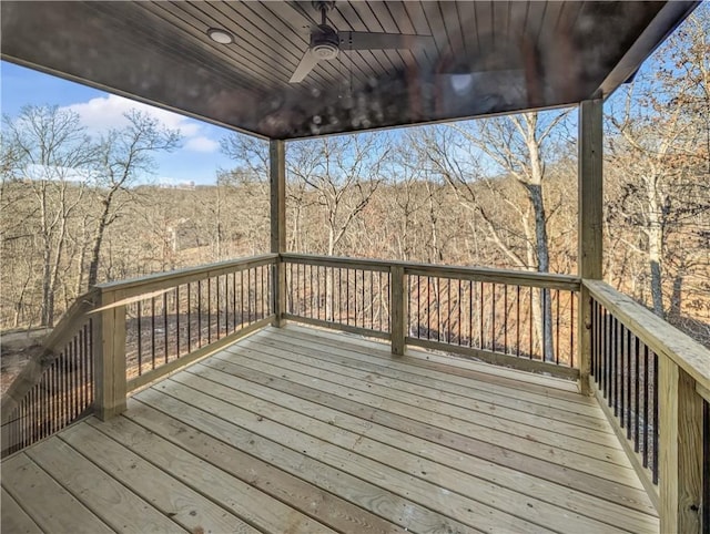 wooden terrace with a wooded view and a ceiling fan