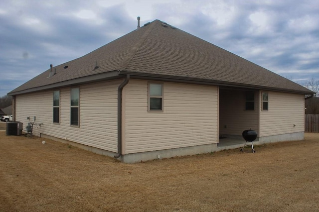 view of home's exterior featuring a yard, central AC unit, and a shingled roof