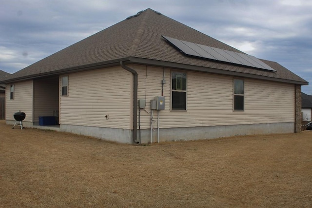 view of side of home featuring solar panels and a shingled roof