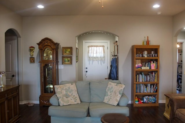 living room featuring recessed lighting, baseboards, arched walkways, and dark wood finished floors