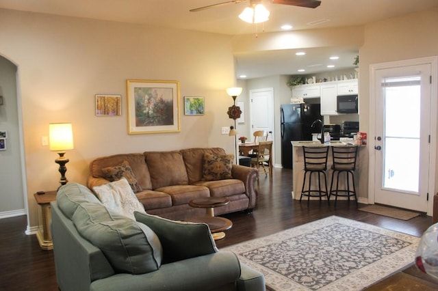 living room with dark wood finished floors, plenty of natural light, baseboards, and a ceiling fan