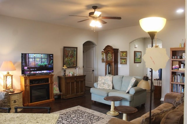 living room with wood finished floors, arched walkways, and ceiling fan