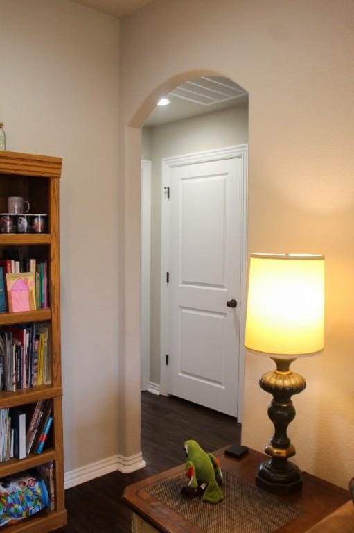 corridor featuring baseboards, arched walkways, visible vents, and dark wood finished floors