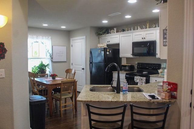 kitchen featuring black appliances, a sink, light stone counters, a peninsula, and white cabinets