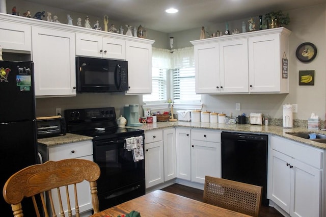 kitchen with white cabinetry, black appliances, and light stone countertops