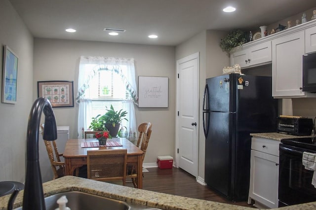 kitchen with visible vents, black appliances, dark wood-type flooring, and light stone countertops