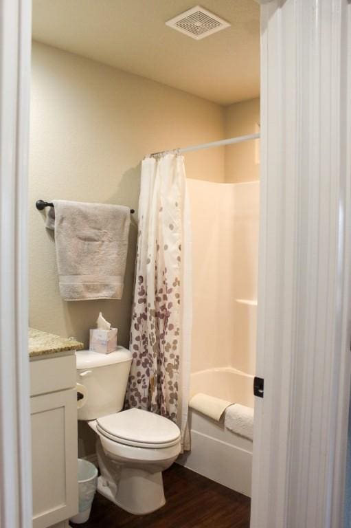 full bathroom featuring visible vents, shower / bath combo with shower curtain, toilet, wood finished floors, and vanity