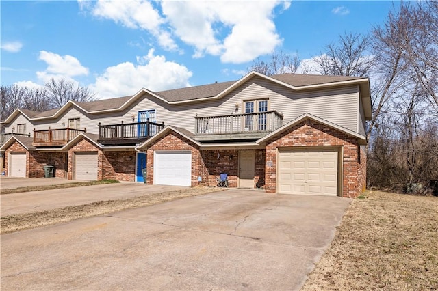 multi unit property with a balcony, an attached garage, brick siding, and driveway