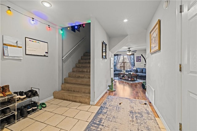 foyer entrance featuring stairway, a ceiling fan, visible vents, and baseboards