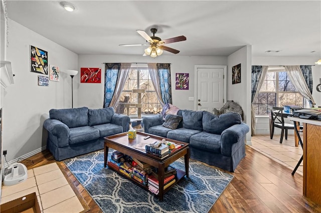 living room with wood finished floors, a ceiling fan, baseboards, and visible vents