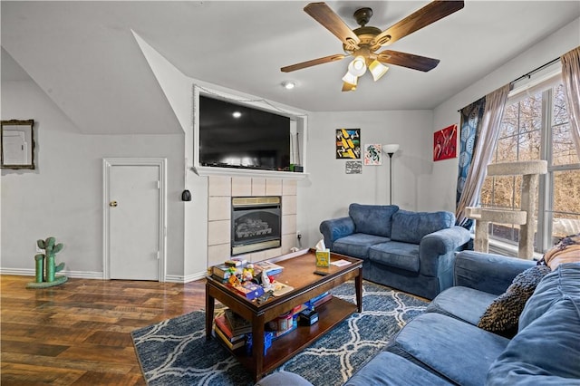 living area with a tiled fireplace, wood finished floors, baseboards, and ceiling fan