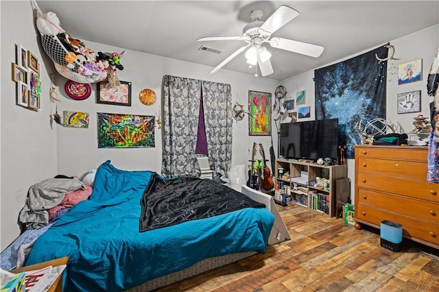 bedroom with wood finished floors, visible vents, and ceiling fan