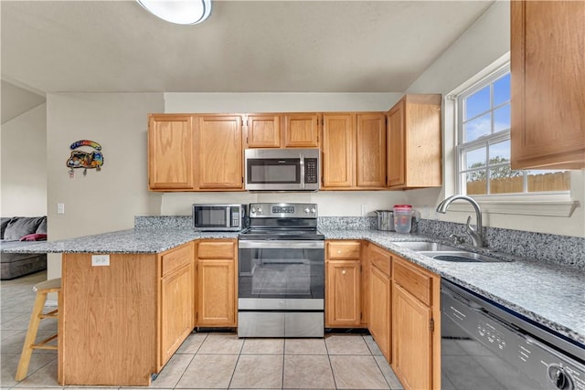 kitchen featuring a breakfast bar area, a peninsula, light tile patterned flooring, stainless steel appliances, and a sink