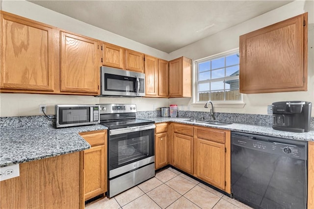 kitchen featuring light stone counters, appliances with stainless steel finishes, light tile patterned flooring, and a sink