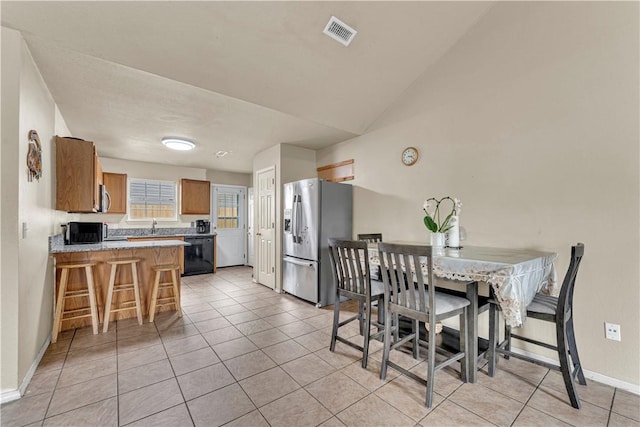 dining area featuring light tile patterned floors, visible vents, baseboards, and vaulted ceiling