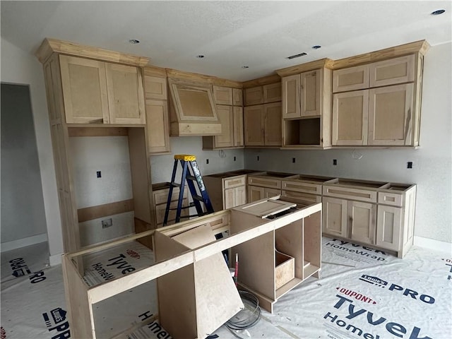 kitchen with custom range hood, light brown cabinets, and baseboards