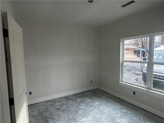 empty room featuring unfinished concrete floors and baseboards