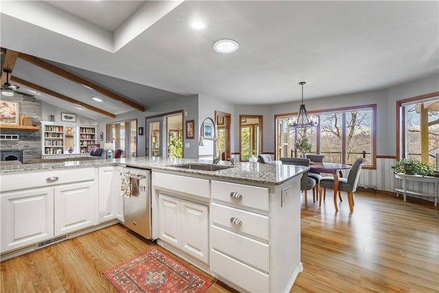 kitchen featuring visible vents, a sink, lofted ceiling with beams, stainless steel dishwasher, and light wood-style floors