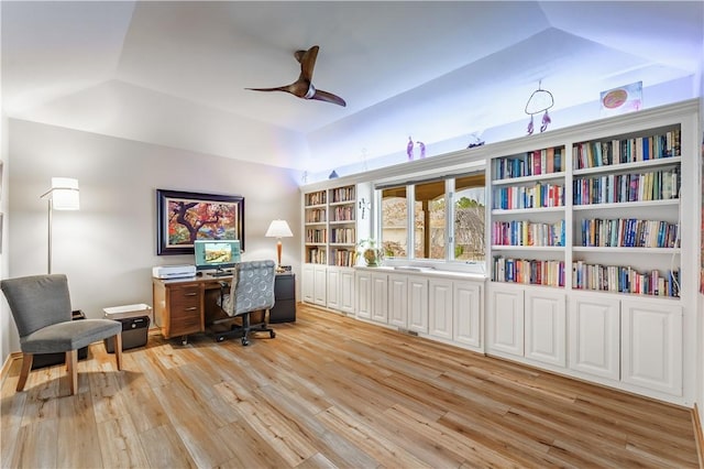 office featuring ceiling fan, a tray ceiling, light wood-style floors, and vaulted ceiling