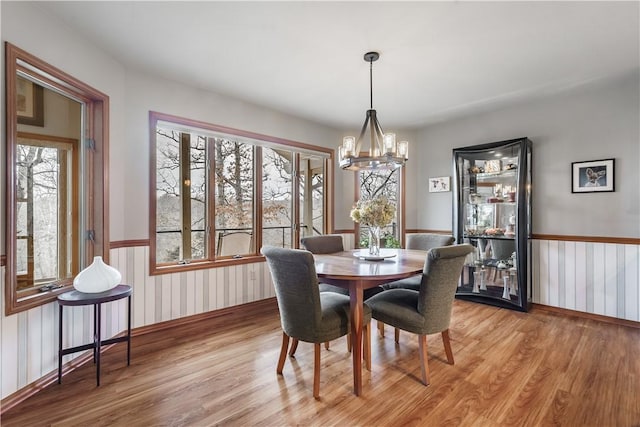 dining area featuring a wainscoted wall, a notable chandelier, and light wood finished floors