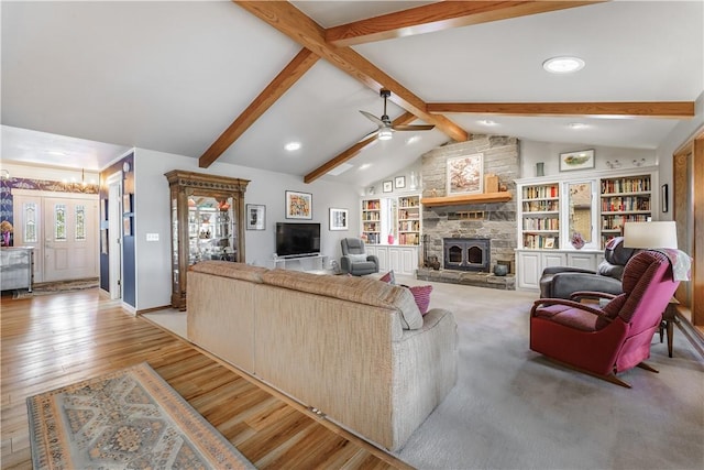 living area with vaulted ceiling with beams, baseboards, a stone fireplace, ceiling fan with notable chandelier, and wood finished floors