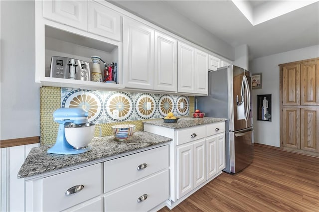 kitchen featuring backsplash, white cabinets, stainless steel refrigerator with ice dispenser, and wood finished floors