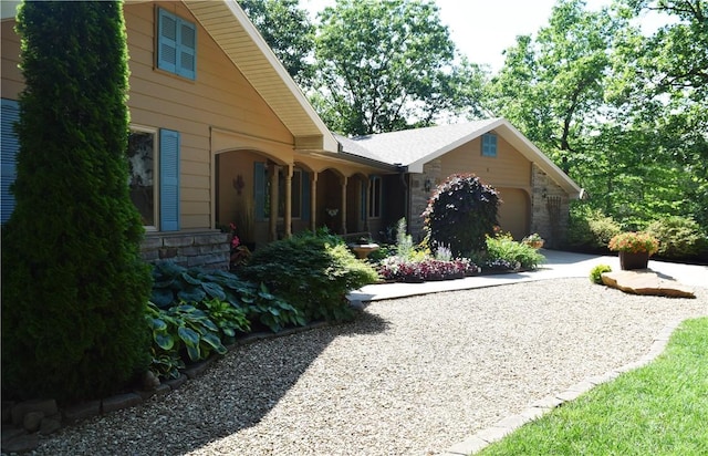 view of property exterior with stone siding, driveway, and a garage