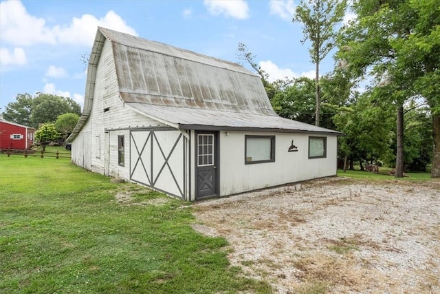 view of barn featuring a lawn and fence