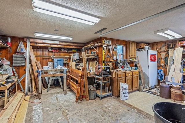 miscellaneous room featuring a workshop area, wood walls, and a textured ceiling