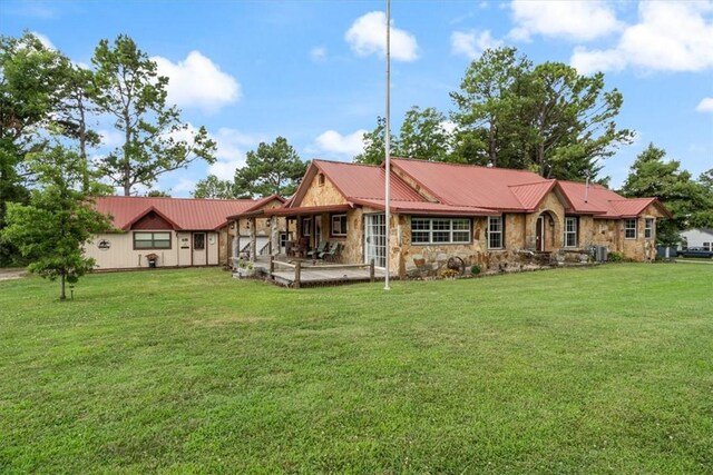 back of house featuring a yard, stone siding, and metal roof