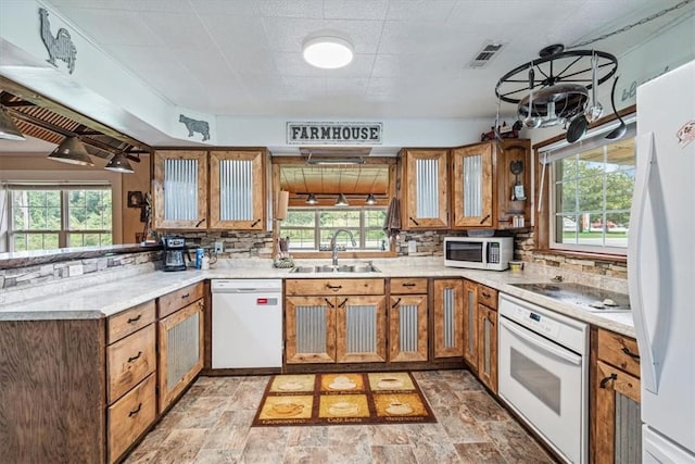kitchen with a sink, brown cabinets, white appliances, backsplash, and visible vents