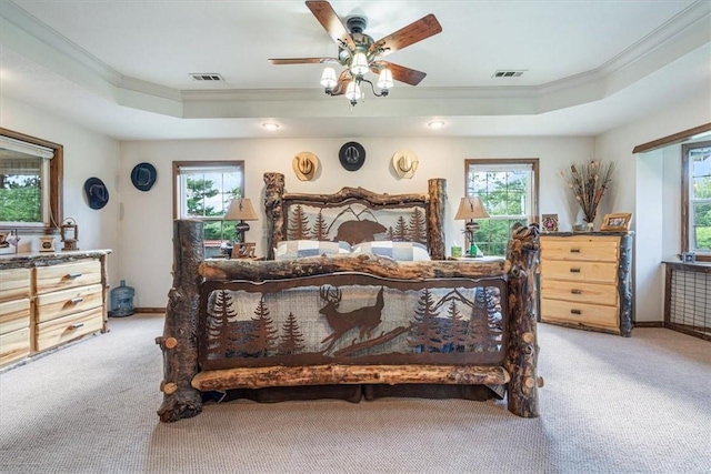 bedroom with light carpet, crown molding, a tray ceiling, and visible vents