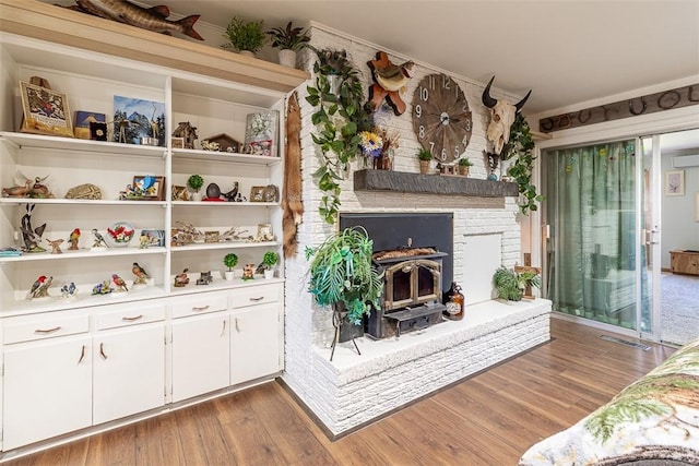 living room featuring a wall unit AC, wood finished floors, visible vents, and ornamental molding