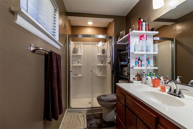 full bath featuring a stall shower, toilet, vanity, and a textured wall