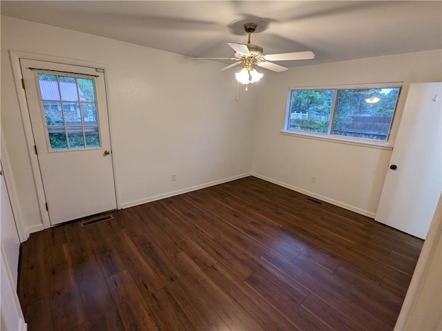 spare room featuring visible vents, dark wood finished floors, ceiling fan, and a wealth of natural light
