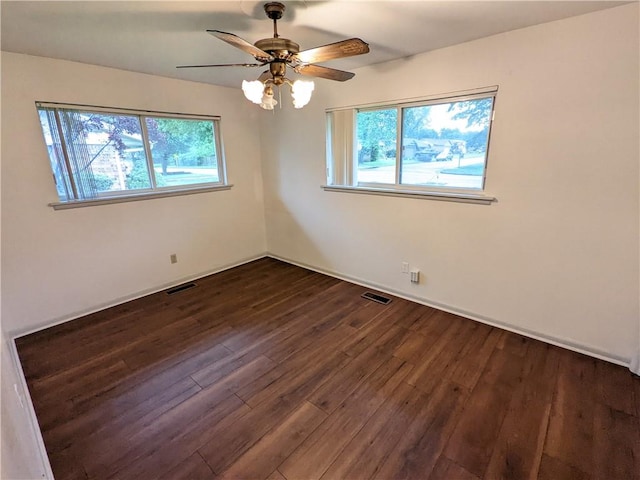 spare room with a healthy amount of sunlight, dark wood-style flooring, and visible vents
