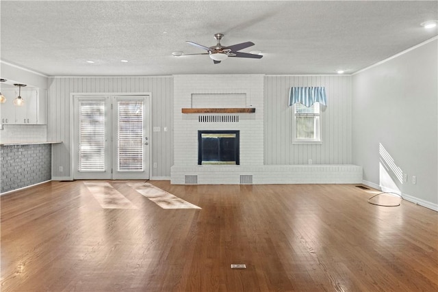 unfurnished living room with ornamental molding, a ceiling fan, a textured ceiling, wood finished floors, and a fireplace
