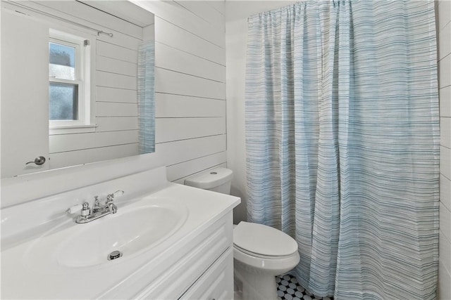 full bathroom featuring vanity, curtained shower, toilet, and wood walls