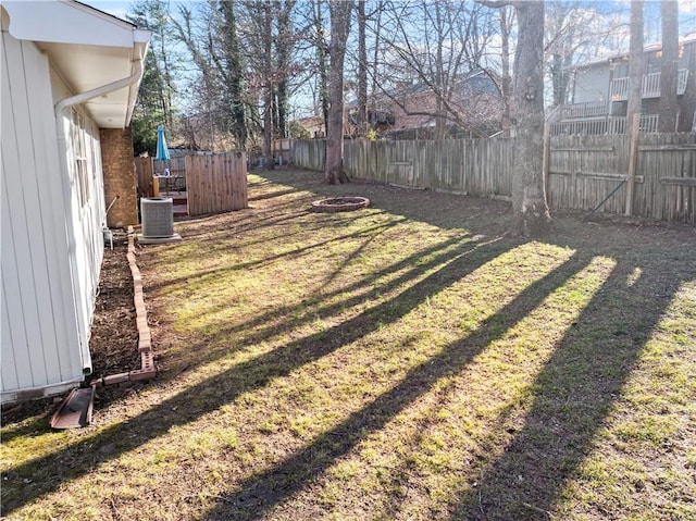 view of yard featuring cooling unit, a fire pit, and a fenced backyard